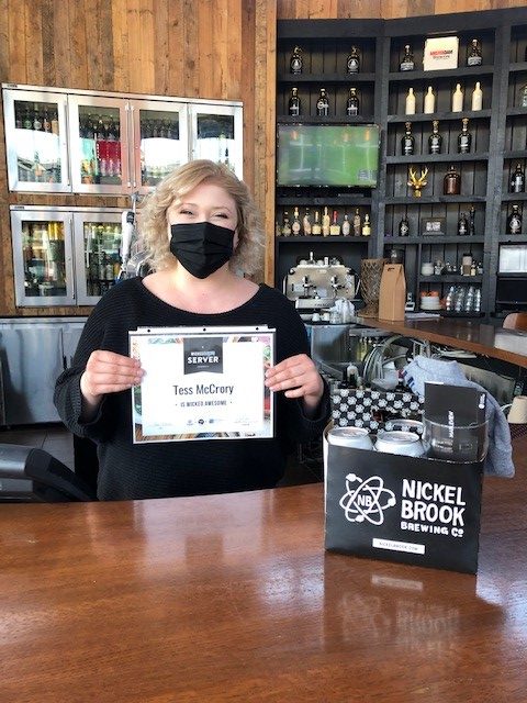 Winner wearing mask and holding certificate behind the bar