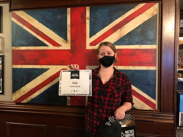 Winner holding certificate standing in front of Union Jack painting on the wall